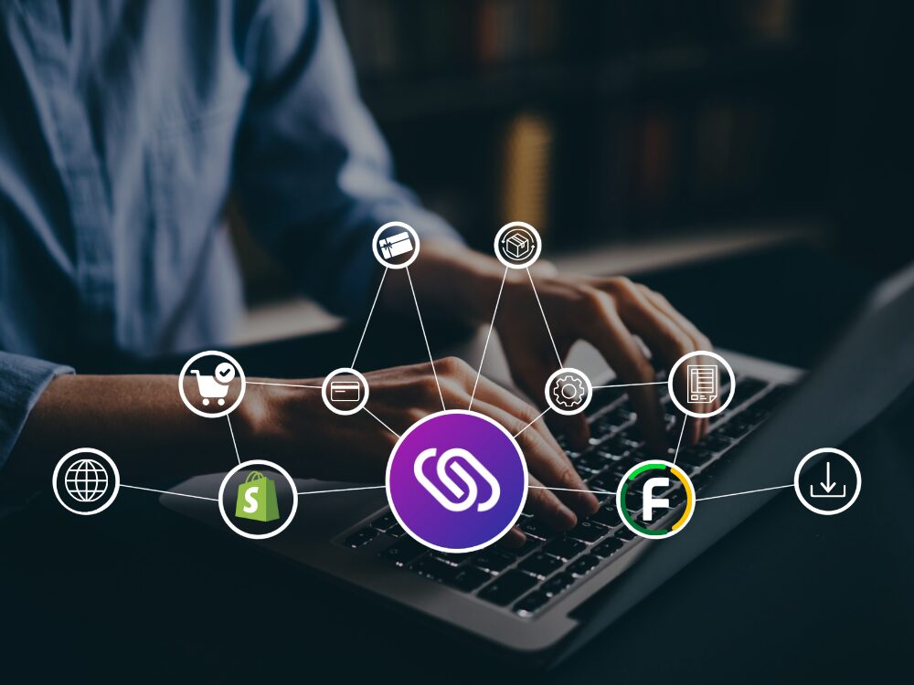 En man som sitter och knappar på en dator. På bilden är det ett nät av en integration mellan Fortnox och Shopify.